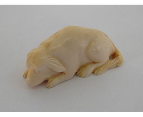 An early 20th century Japanese carved ivory katabori netsuke, modelled as reclining dog, incised character signature to base,