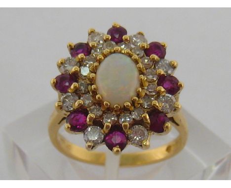 An 18 carat yellow gold, diamond and ruby dress ring, the central oval white opal 7.5mm long, in a surround of alternate roun