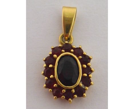 An 18 carat yellow gold and garnet pendant, the central oval stone 6.4mm, in a surround of smaller garnets, hallmarked to the