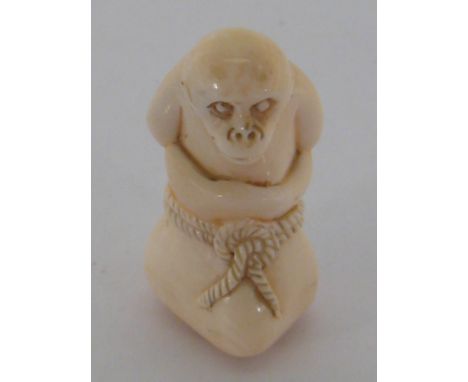 An early 20th century Japanese carved ivory katabori netsuke, modelled as a bound monkey in a bag, incised character signatur