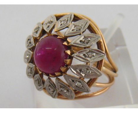 An 18 carat yellow gold, platinum, ruby and diamond dress ring, the central cabochon 7.8mm diameter, in an open work surround