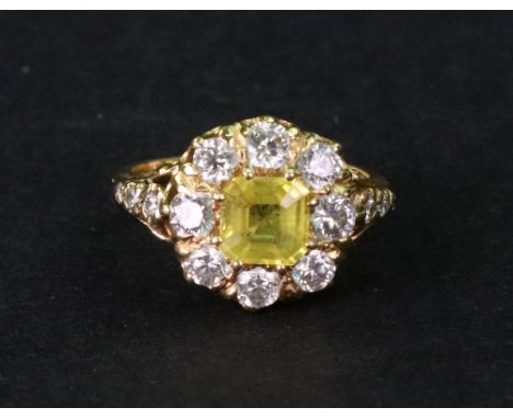 A modern yellow sapphire and diamond cluster ring, centred with a cut-corner square yellow sapphire approximately 1.25cts, wi