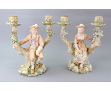 A pair of Royal Worcester Watteau style figure candelabra, circa 1885, each modelled as young male and female subjects seated