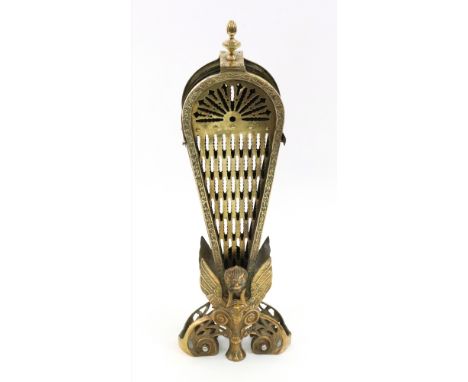 A gilt metal fan shape fireguard, 20th century, with pierced panel, the base cast with winged masks on claw feet flanked by l