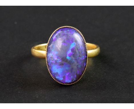 A late Victorian gold and black opal single stone ring, the oval cabochon approx. 15mm x 11mm, millegrain set to a plain 22ct