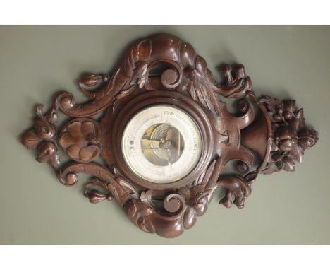Early 20th century aneroid barometer, carved oak case decorated with fruit above winged beasts and scroll leafage, silvered d