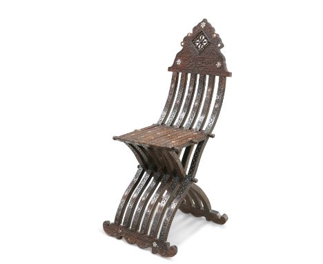 A SYRIAN FOLDING SCRIBES CHAIR, LATE 19TH CENTURY, the wavy X-form frame carved with foliage and inlaid with mother-of-pearl,