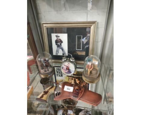 Shelf of John Wayne collectables items . 