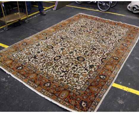 A large modern Persian handwoven carpet with a beige central field and floral decoration with an orange border. 293cm x 193cm