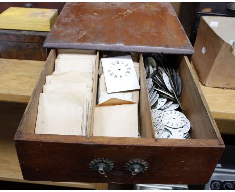 A pine two drawer cabinet, containing a large quantity of enamel watch faces, springs and other items.