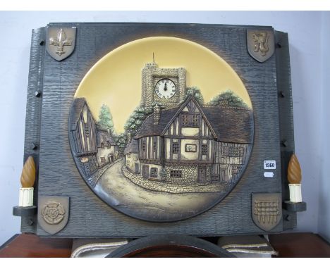 A Shellcraft Porcel Ware Wall Clock, in ceramic village scene plaque within rectangular shield mounted plaque holding twin ca