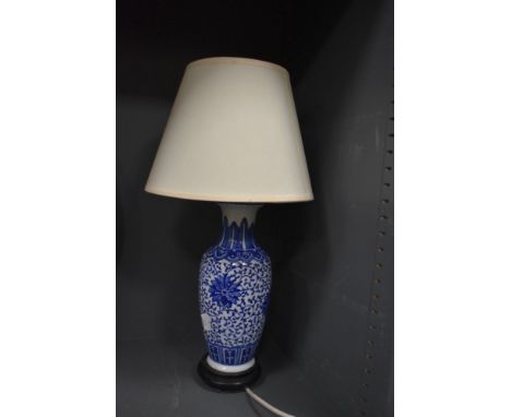 A blue and white ceramic patterned table lamp with wooden base and cream shade.