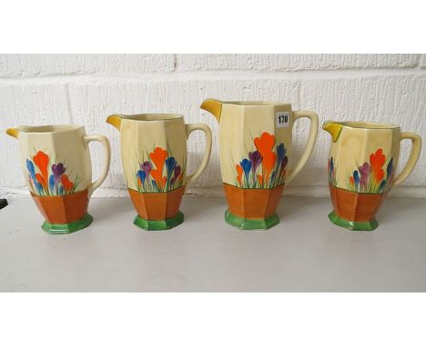 A Clarice Cliff pottery set of three graduated jugs in the Crocus pattern, along with a later similar jug
