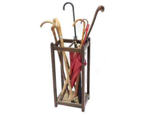 A 20thC oak stick stand, and various parasols and walking sticks, the stand 69cm high, 30cm wide, 25cm deep.