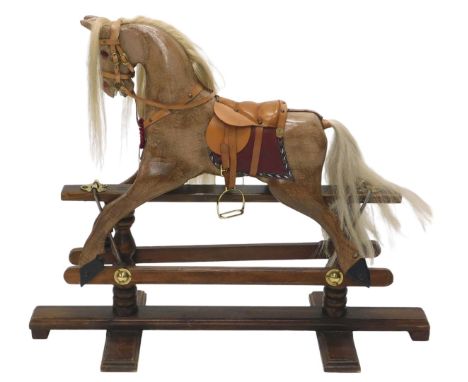 A 20thC rocking horse, the brown wooden painted horse on oak base, with red and brown leatherette saddle with rosette, 86cm h