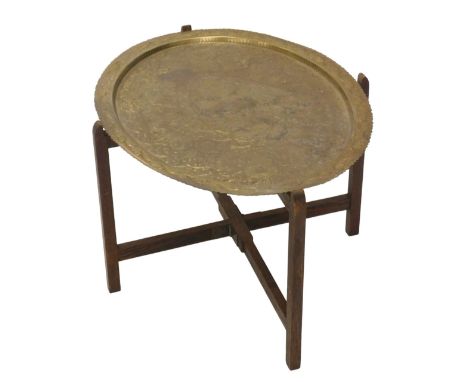 An Eastern hammered brass oval tray table, the brass tray with engine engraved scroll and floral decoration, 69cm x 54cm, on 