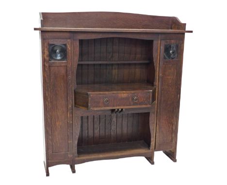 A 1920's Liberty &amp; Co Arts and Crafts oak cabinet, with gallery top, open centre section below with a narrow shelf and br