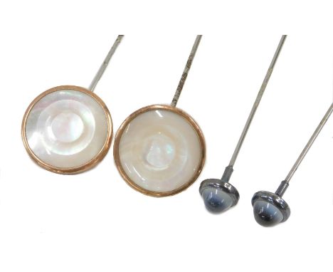 Four various hat pins, comprising two thistle topped and silver rimmed pins, and two mother of pearl and yellow metal button 
