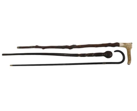 Three walking sticks, including an antler handled stick, an African hardwood club on stick, and a walking cane.