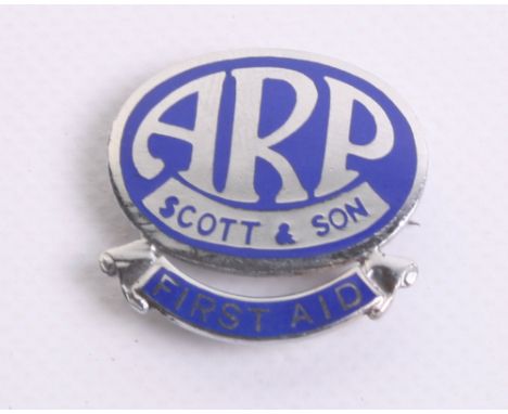 WW2 Home Front ARP Scott & Son Lapel Badge of chrome with blue enamel. Bottom of the badge has a scroll with FIRST AID. Rever