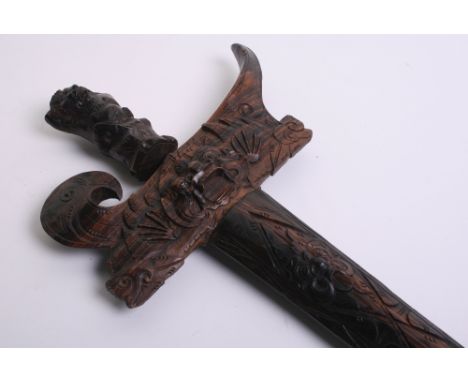 Balinese Kris with wavy watered steel blade. Carved wood handle and scabbard. 65 ½ cm in length, blade measures 38 ½ cm in le