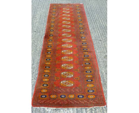 A red ground runner. 253 x 80 cm.