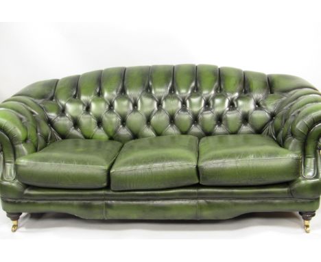 A green buttoned leather scroll sofa, armchair and stool