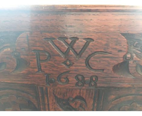 A James II carved oak and elm settle, dated 1688
The running leaf carved top-rail with turned finials and four strap-work car