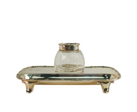 Edward VII hallmarked silver ink stand with silver topped clear glass inkwell and pen tray, with detail to rim raised on four