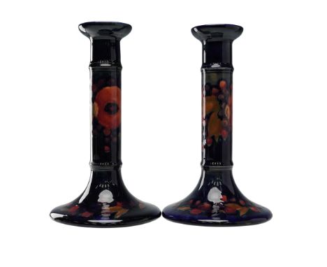 Pair of Moorcroft pottery candlestick holders featuring a hand-decorated pomegranate and berries design. The cylindrical stem