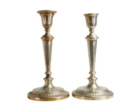 Matching pair of silver candlesticks with fluted urn shaped sconces. Features a tapering stem with a fluted and reeded base. 