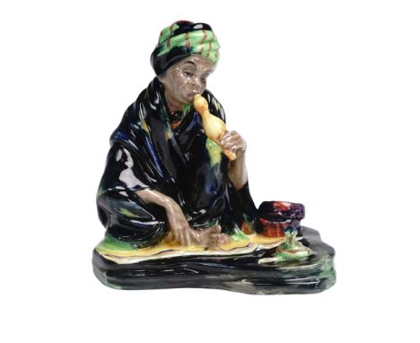 Royal Doulton porcelain figurine titled The Snake Charmer, model HN1317. This early figure portrays a seated male snake charm