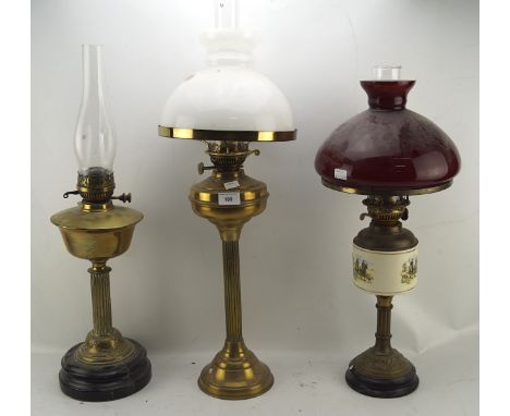 Three Victorian oil lamps, all with brass column frames on circular bases, one with a ceramic reservoir decorated with a ridi