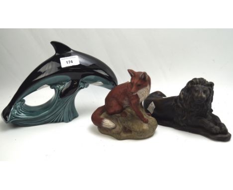Two Poole pottery animals and a resin sculpture of a lion, the Poole animals comprising of a dolphin and a fox, the lion in a