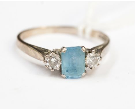 An 18ct white gold aquamarine and diamond ring, the baguette cut central stone, aquamarine, is approximately 0.75ct, the diam