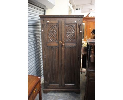 An oak double wardrobe, by Richardsons of Highgate, the two doors opening to reveal a shelf and a hanging rail below.