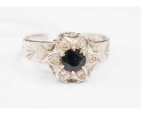 An 18ct white gold diamond and sapphire dress ring 'M' the central sapphire surrounded by diamond chips, 4.0 grams approx 