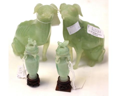 A pair of Chinese carved jade dogs together with a pair of lidded vases, each with rings handles to the necks, on wooden plin