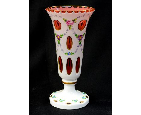 A Bohemian ruby glass trumpet shaped vase, white overlay painted with flowers, gilt lined, circular base, 20 cm high