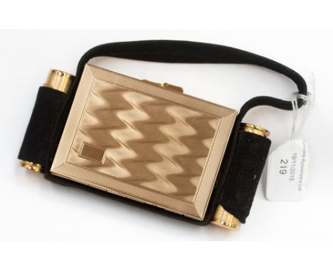 A Kigu of London compact, circa 1950s, engine turned gilt metal, in a suede holder with handle, unused, with powder puff, lip