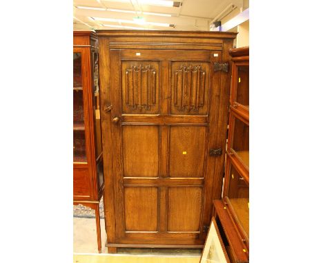 A Tudor style oak hall cupboard, of pegged mortise and tenon construction, the single six panelled door with two linen-fold p