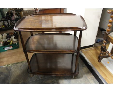 An Ercol Windsor dark elm and beech three tier trolley, on wheels, 72cm wide, 74cm high, 47cm deep