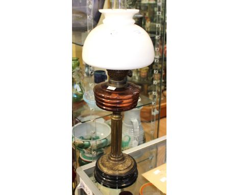 A late Victorian oil lamp with reeded brass column, coloured glass reservoir, shade and chimney, 43 cm in height approx 