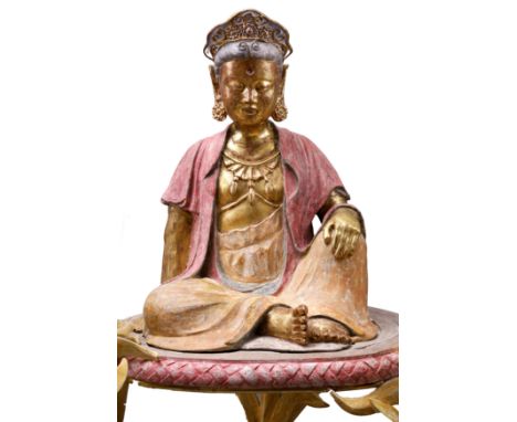 A Chinese polychrome and gilt stucco figure of a seated GuanyinMing dynastySeated with one hand resting on a raised knee, wea