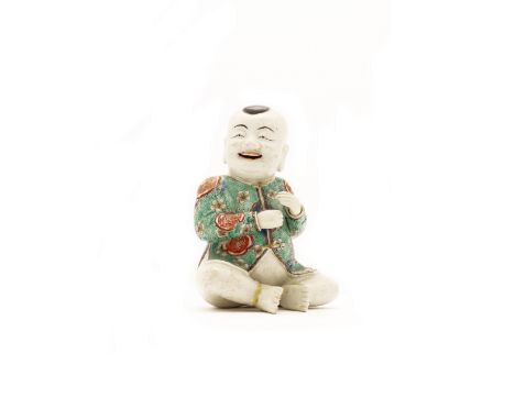 A Chinese famille verte on biscuit 'laughing boy' figureQing dynasty, Kangxi periodModelled as a young boy seated wearing a j