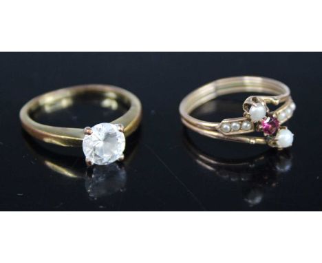 A yellow metal, ruby and seed pearl set crossover ring, size N; together with a gilt metal and paste set dress ring (2)