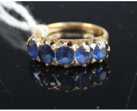 A yellow metal and sapphire set half-hoop ring, arranged as five round cut sapphires, each measuring approx 5.2 x 4.5 x 2.75m