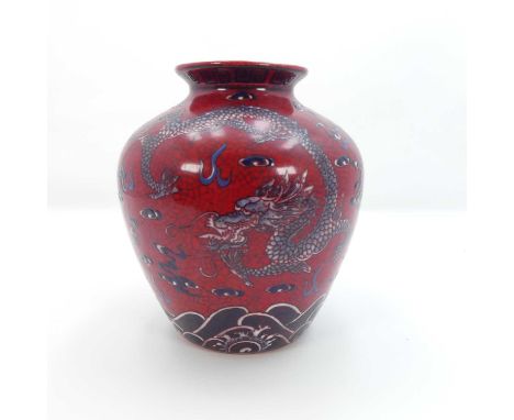 A Chinese porcelain vase of shouldered form, enamel decorated with a dragon amongst clouds on a red ground, bearing a four ch