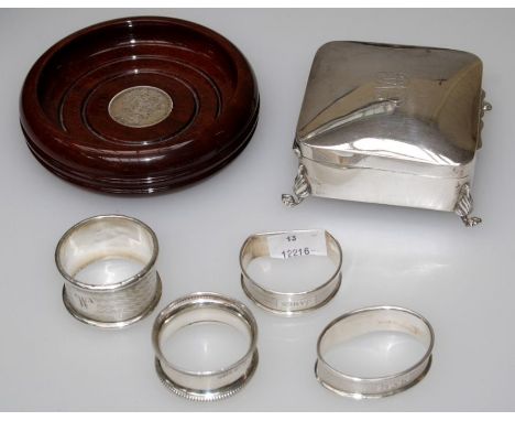 A silver mounted turned wood bottle coaster, a silver ring box on four paw feet and four silver serviette rings, various date