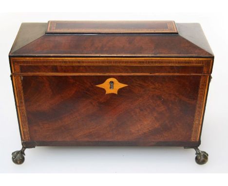 A Regency figural mahogany and line inlaid two division tea caddy of sarcophagus shape on ball and claw feet